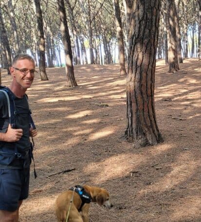 Escursionista con zaino e cane nella pineta della Riserva Naturale del Tombolo