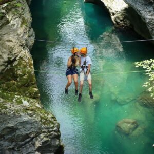 Due persone sospese su una zip line al Canyon Park di Bagni di Lucca, sopra le acque turchesi del fiume Lima